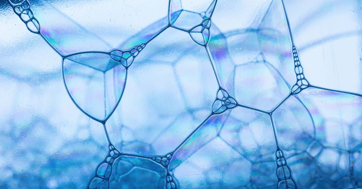 Close-up view of soap bubbles with a reflective blue hue, showcasing geometric patterns.